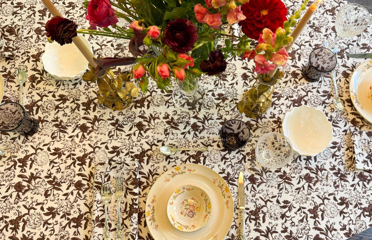 Decorative antique and traditional table setting with floral centerpiece and brown and white sara khatib chocolate wildflower patterned tablecloth